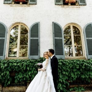 Elegant bride and groom share a joyful moment outside a charming Parisian building.
